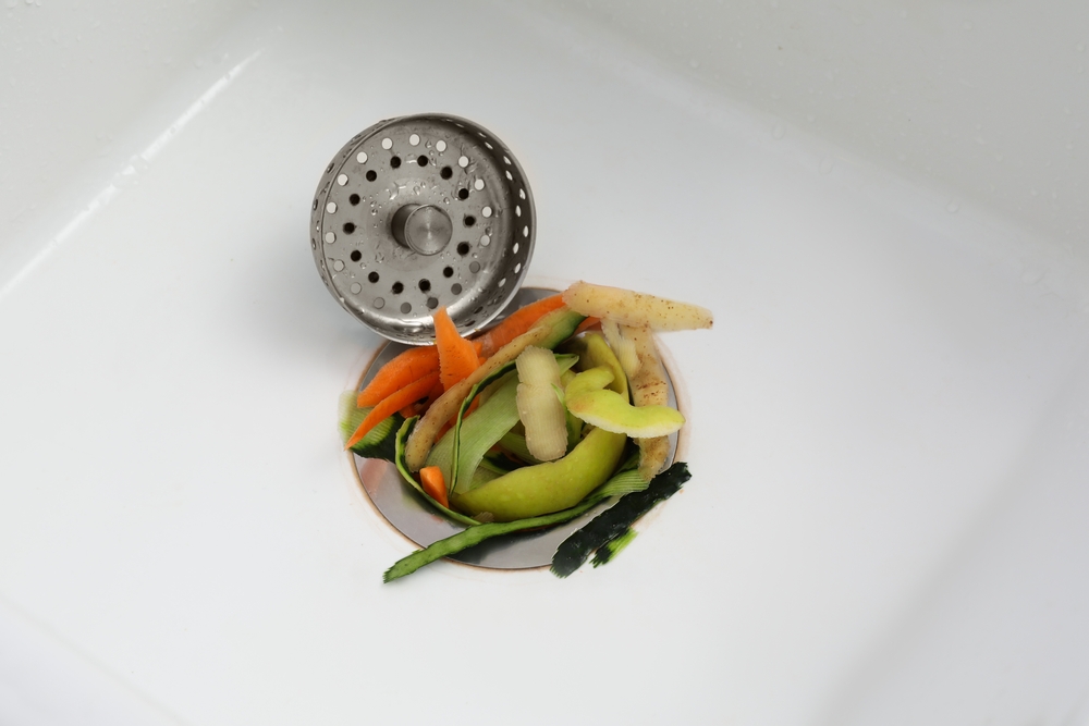 Professional plumber repairing a garbage disposal that won't spin after a summer BBQ cleanup
